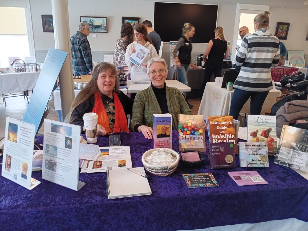 Billie Ortiz (Wake Up To Your Dreams) and Laura Deal (First Church of Metaphor) sitting at a table with their promotional materials at the Niwot Wellness Day. 